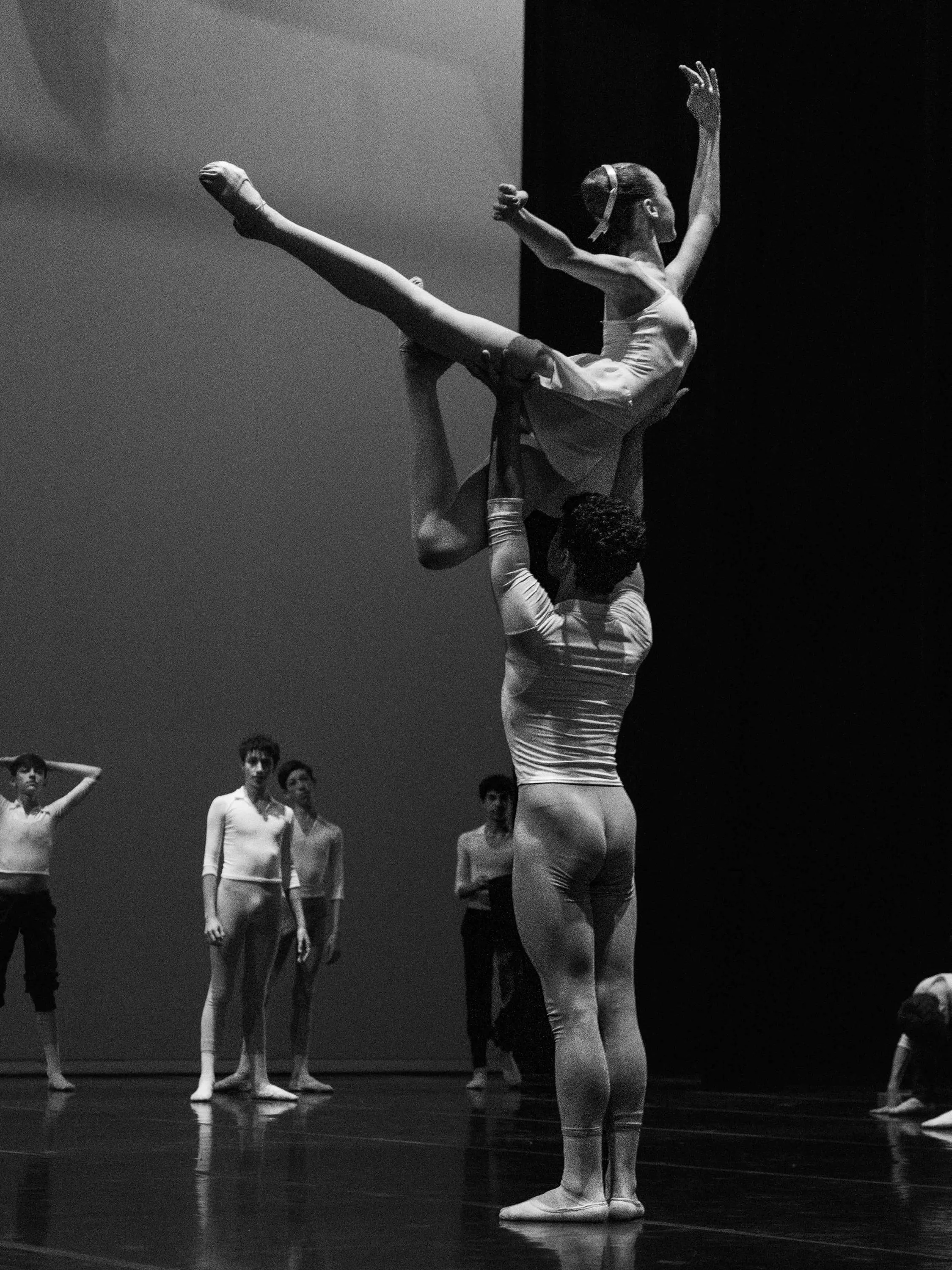 Una ballerina sollevata in alto dal compagno durante la prova