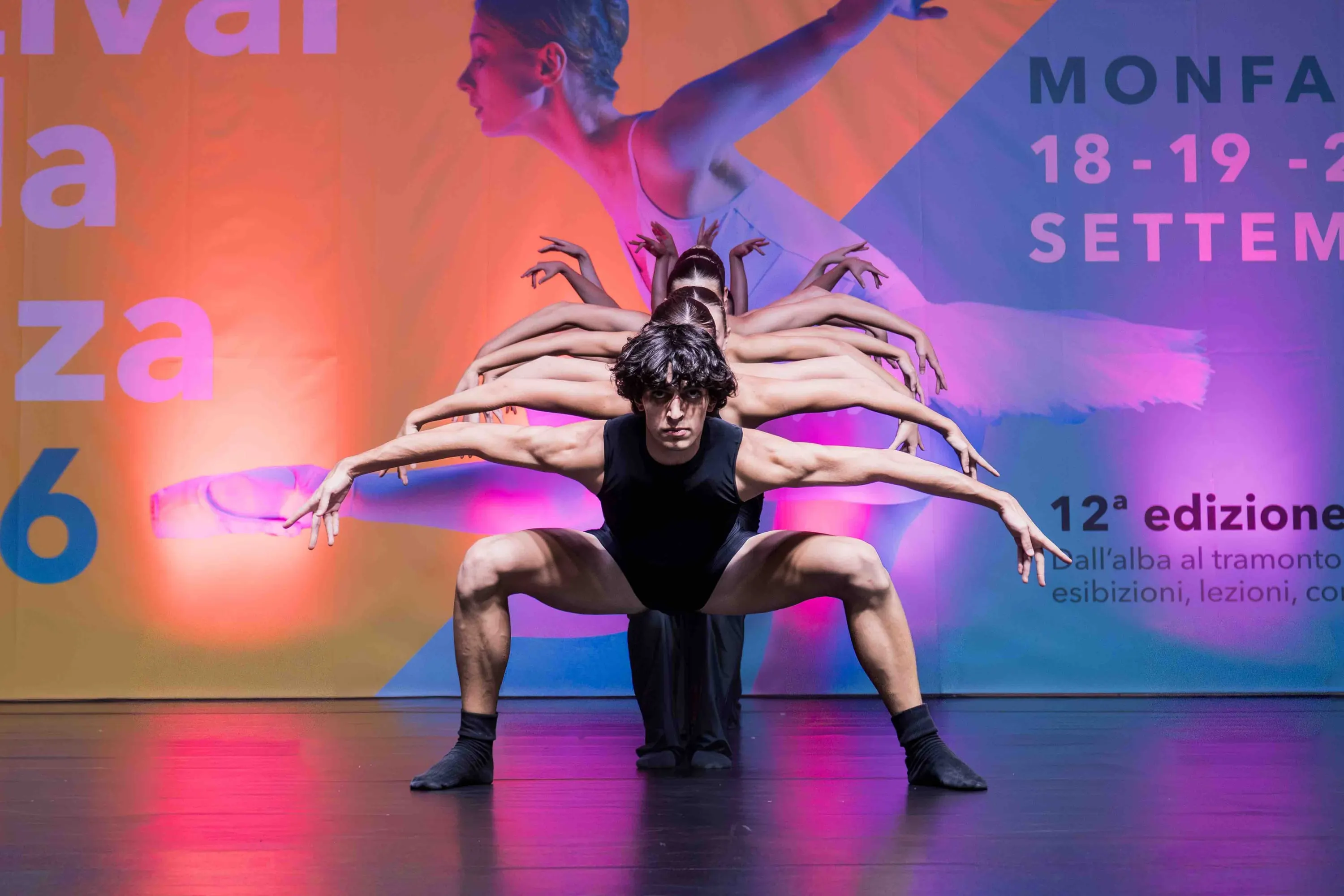 Un danzatore in primo piano con molte braccia aperte a raggiera dietro di lui
