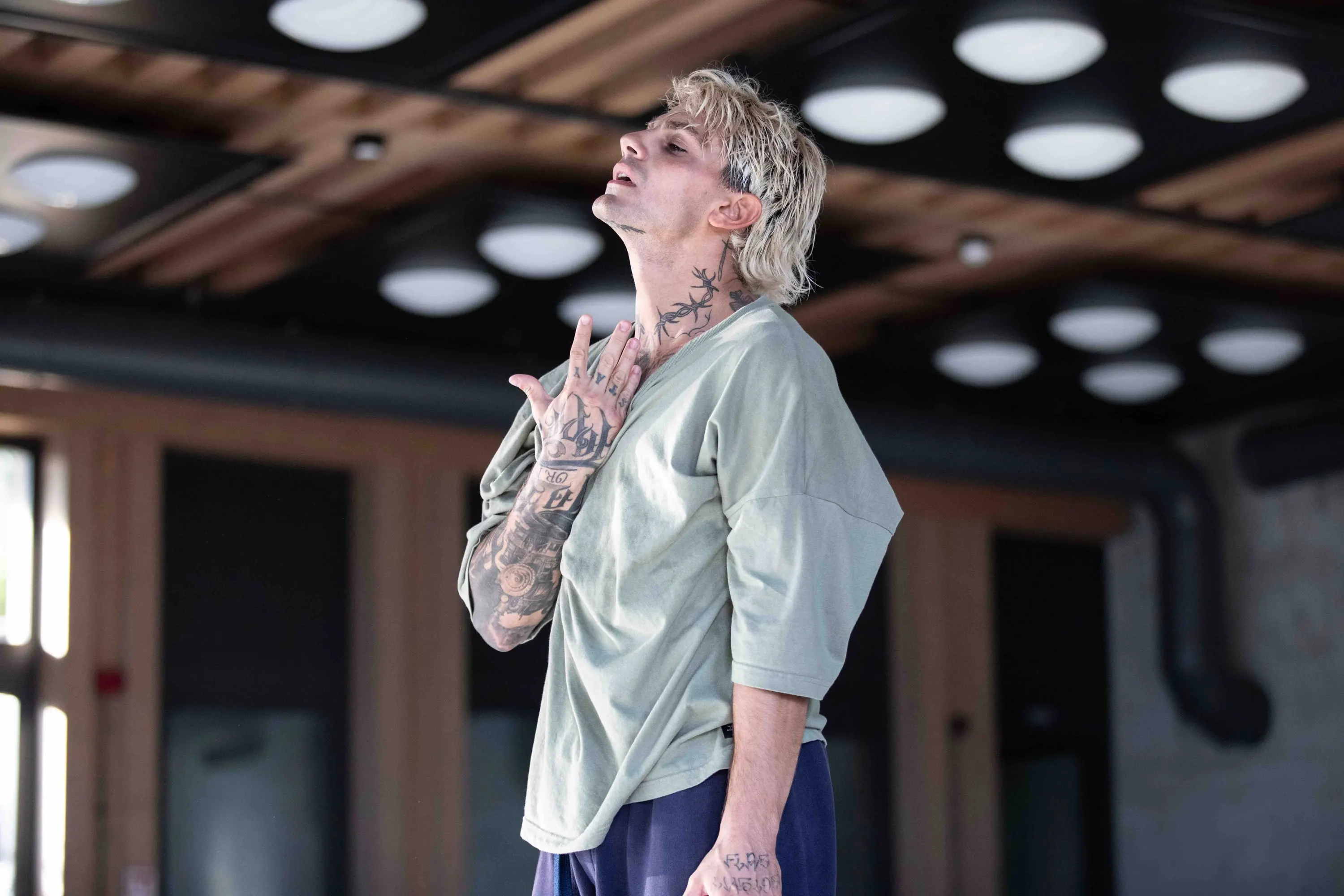 Un danzatore con tatuaggi alza lo sguardo in sala prove