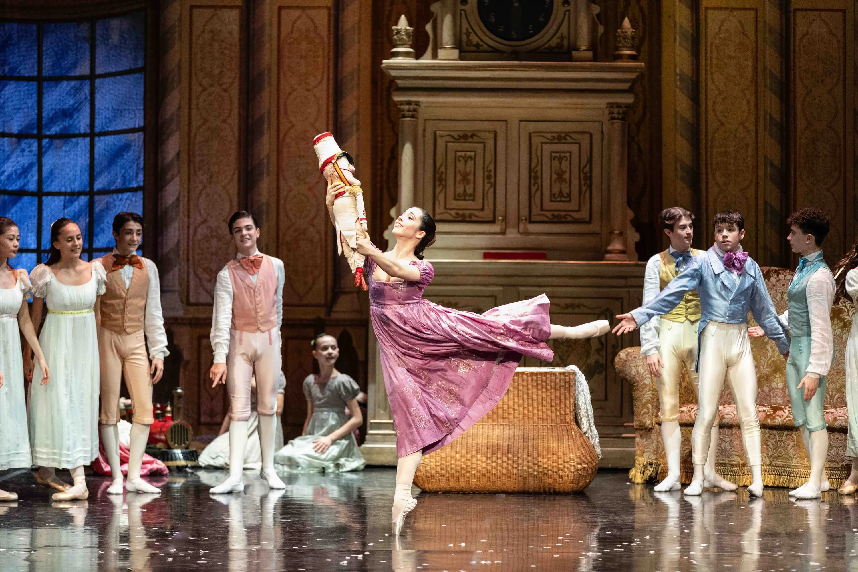 Scena della festa: una ballerina in rosa in arabesque tra gli ospiti