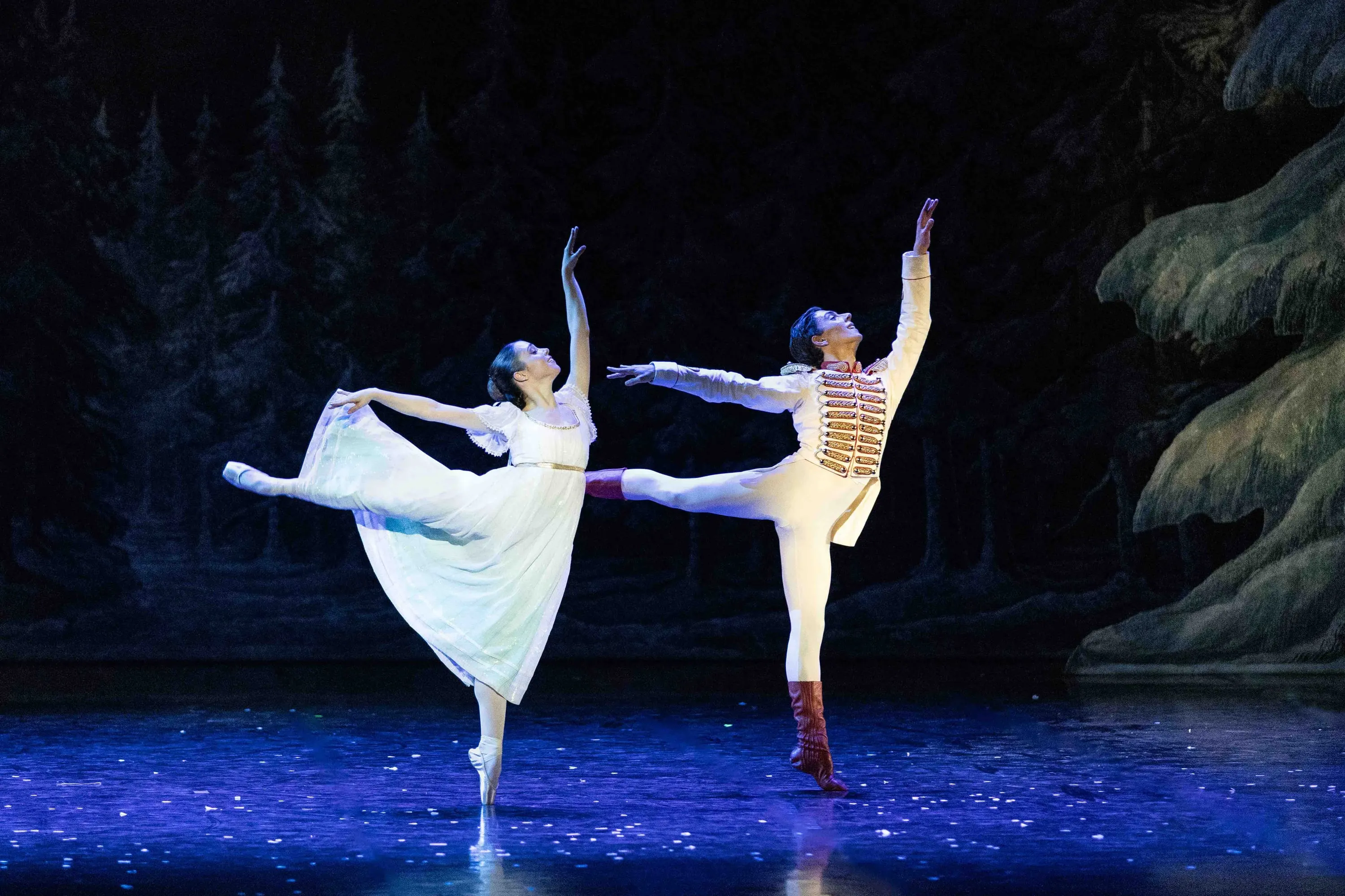 Due ballerini in arabesque nel bosco innevato, in luce blu