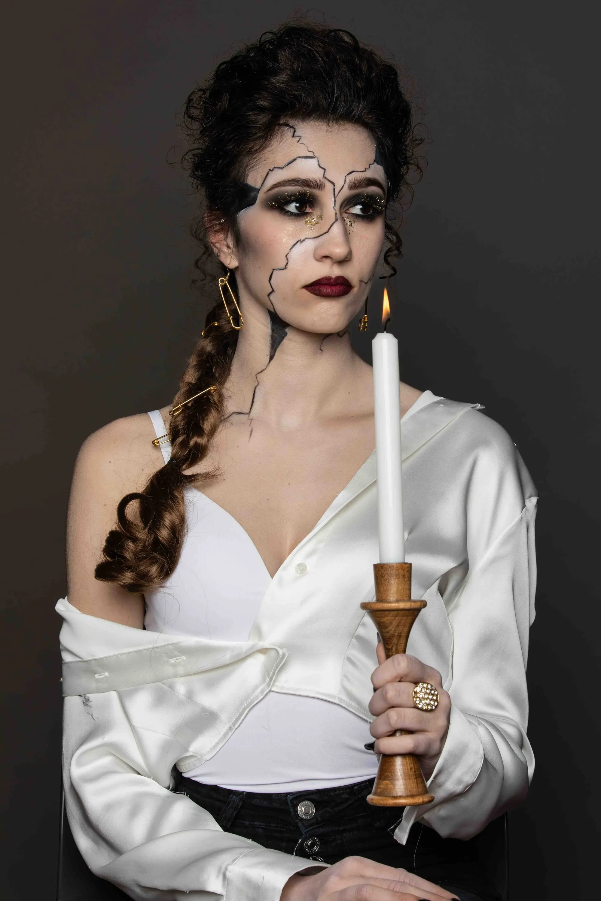Trucco teatrale con crepe sul viso, la modella regge una candela