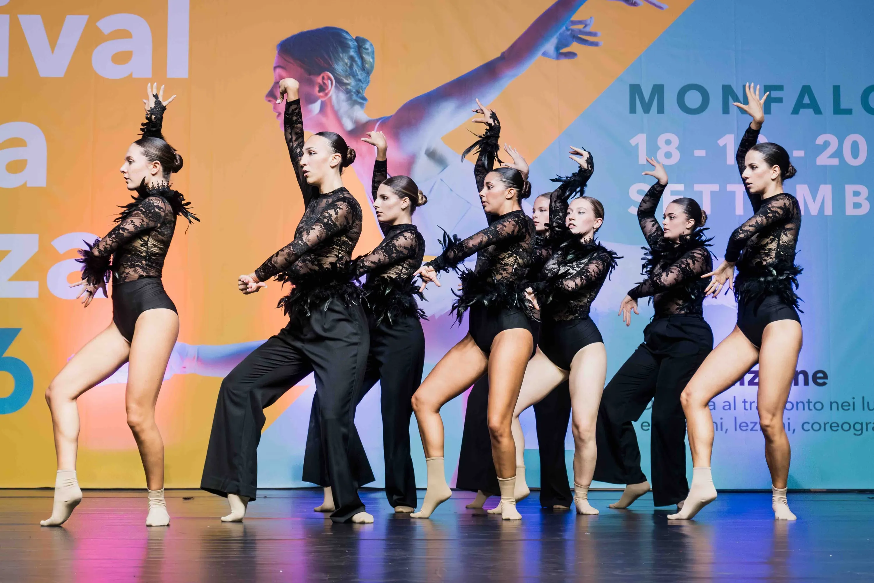 Gruppo di danzatrici in nero con piume, in posa decisa