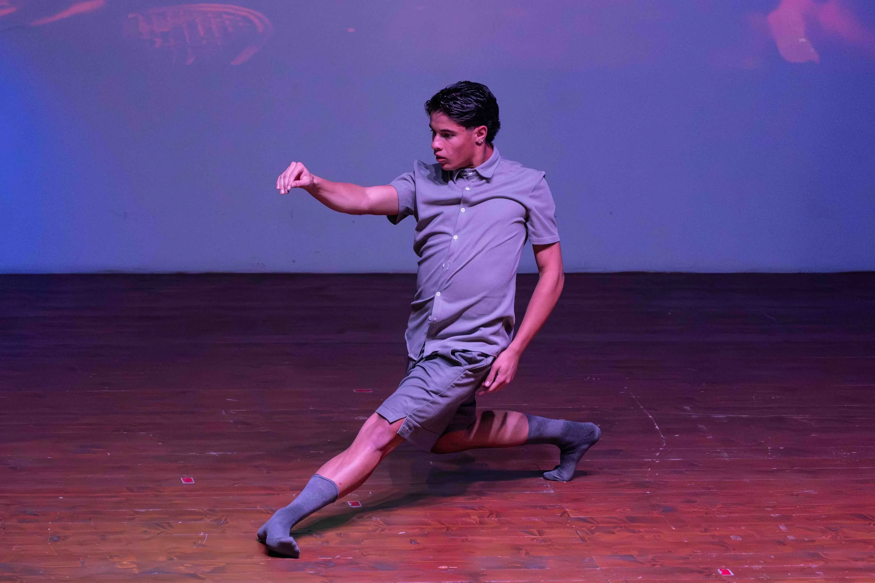 Un giovane danzatore in affondo sul palco, in luce viola